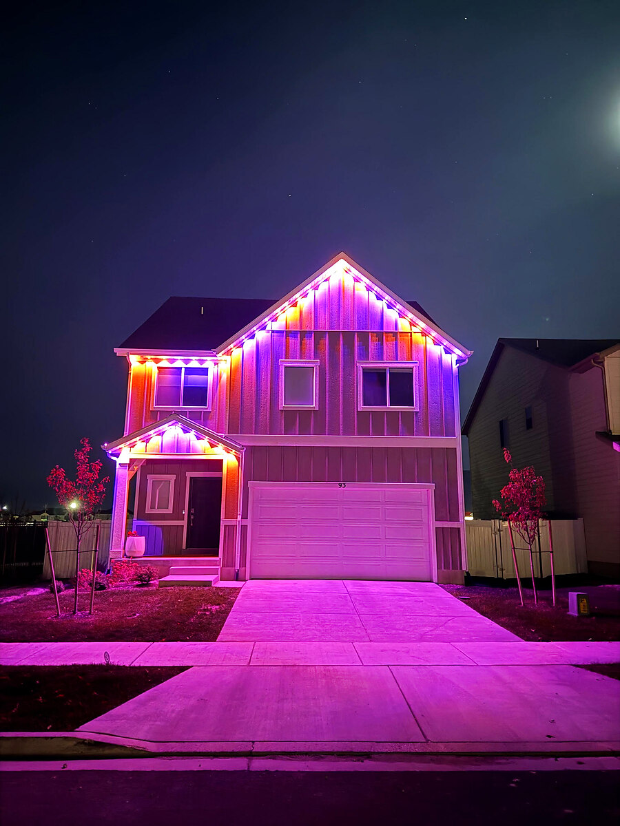 Permanent roofline lighting in pink and purple on a two-story home